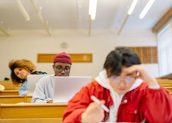 Diverse group of college students focused on studying in a university classroom setting.