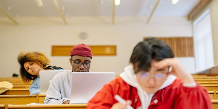 Diverse group of college students focused on studying in a university classroom setting.