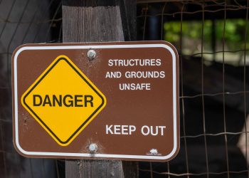 Danger sign warning about unsafe structures and grounds with keep out notice.