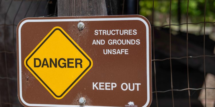 Danger sign warning about unsafe structures and grounds with keep out notice.