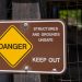 Danger sign warning about unsafe structures and grounds with keep out notice.