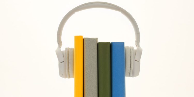 White headphones resting on colorful books, symbolizing modern audio technology.