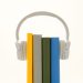 White headphones resting on colorful books, symbolizing modern audio technology.