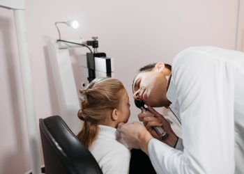 A doctor examines a young girl's ear during a medical appointment in a clinic.