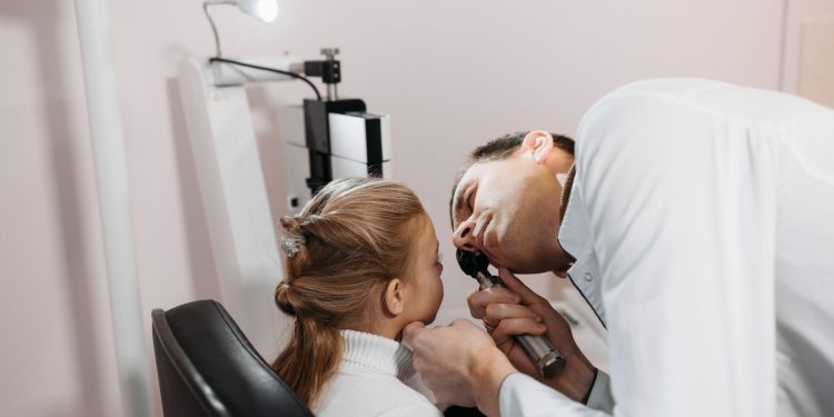 A doctor examines a young girl's ear during a medical appointment in a clinic.