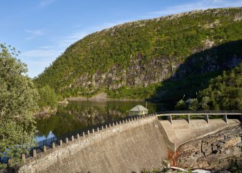 A picturesque view of a water dam nestled in a mountainous landscape reflecting calm waters.