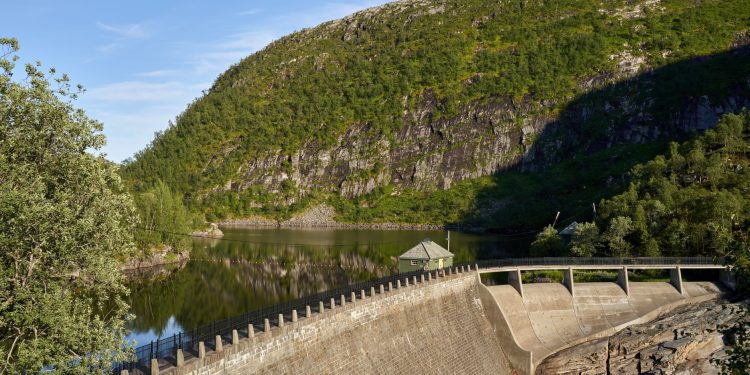 A picturesque view of a water dam nestled in a mountainous landscape reflecting calm waters.