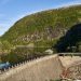 A picturesque view of a water dam nestled in a mountainous landscape reflecting calm waters.