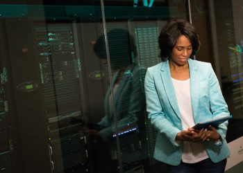 Female IT professional examining data servers in a modern data center setting.