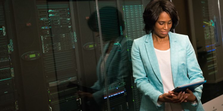 Female IT professional examining data servers in a modern data center setting.