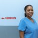 Happy healthcare worker in scrubs standing near emergency room sign.