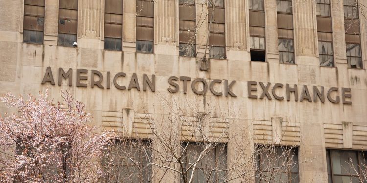 Facade of the American Stock Exchange Building in New York City during spring with blooming trees.