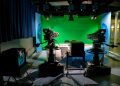 A TV studio setup featuring cameras and a green screen for production purposes.
