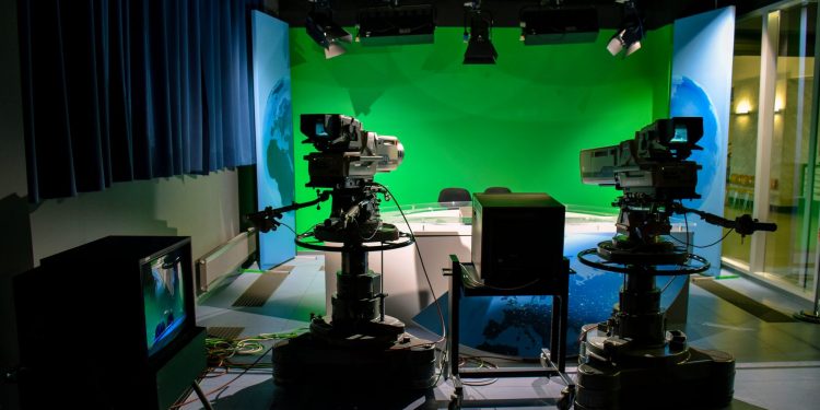 A TV studio setup featuring cameras and a green screen for production purposes.