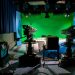 A TV studio setup featuring cameras and a green screen for production purposes.