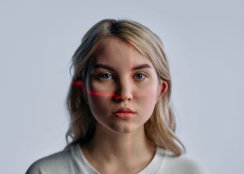 Close-up of a young woman with facial recognition lasers projected, symbolizing future technology.