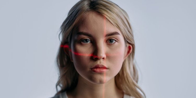 Close-up of a young woman with facial recognition lasers projected, symbolizing future technology.