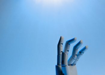 Robotic hand with articulated fingers reaching towards the sky on a blue background.