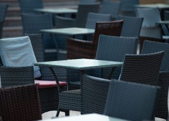 Empty outdoor terrace with wicker chairs and tables, creating a cozy café atmosphere.