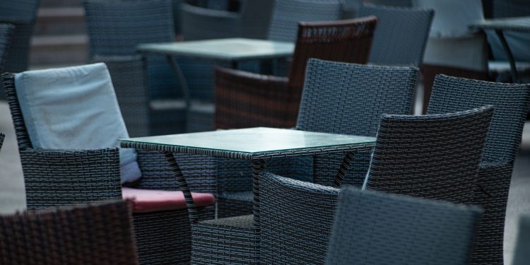 Empty outdoor terrace with wicker chairs and tables, creating a cozy café atmosphere.