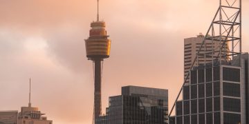 A captivating view of Sydney Tower among modern skyscrapers during sunset, showcasing urban architecture.