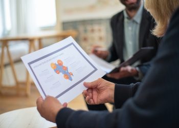 Three professionals discussing a data presentation in an office setting.