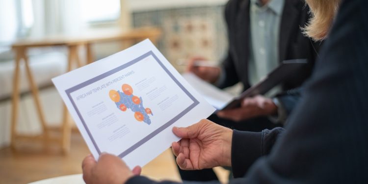 Three professionals discussing a data presentation in an office setting.