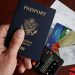 A close-up of a US passport with credit cards, tickets, and a mobile phone on a table.