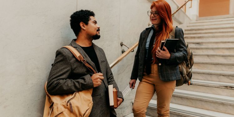 Adult students discussing in a university building on a marble staircase in Buenos Aires.