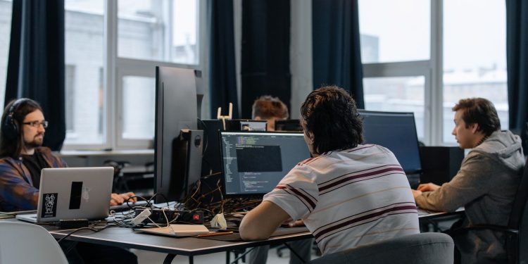 Team of developers working together on computers in a modern tech office.