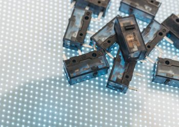 Macro photo of black electronic switches on illuminated LED surface, highlighting technology components.