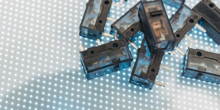 Macro photo of black electronic switches on illuminated LED surface, highlighting technology components.