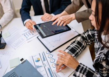 Business professionals reviewing analytics on a tablet during a meeting.
