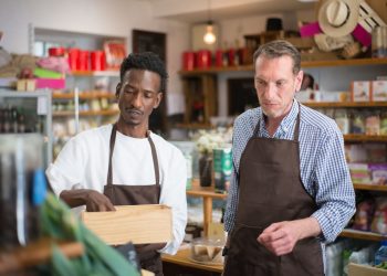 Two male employees organizing products in a cozy grocery store.