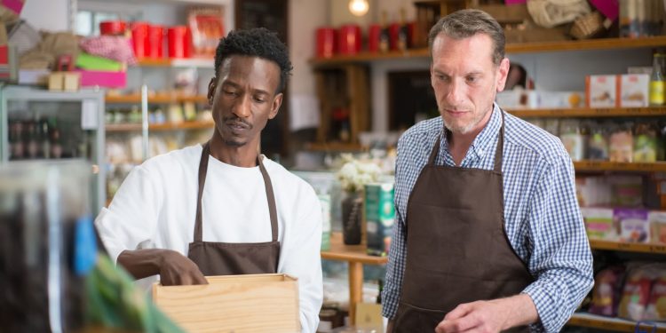 Two male employees organizing products in a cozy grocery store.