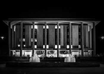 Monochrome image showcasing the National Library of Australia with illuminating fountains at night.