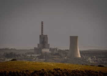 Distant view of a power plant with cooling towers amidst a vast landscape, illustrating energy production.