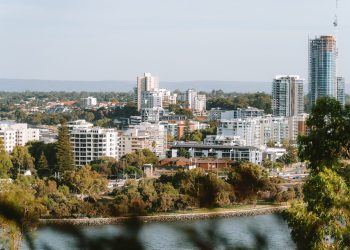 A beautiful day view of Perth city skyline with lush greenery and Swan River.