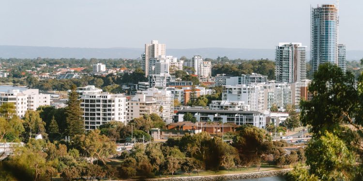 A beautiful day view of Perth city skyline with lush greenery and Swan River.
