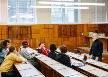 University students in a diverse classroom engaging in a discussion with their professor.