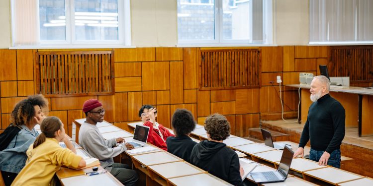 University students in a diverse classroom engaging in a discussion with their professor.