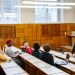 University students in a diverse classroom engaging in a discussion with their professor.