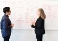 Two professionals brainstorming digital marketing ideas on a whiteboard.
