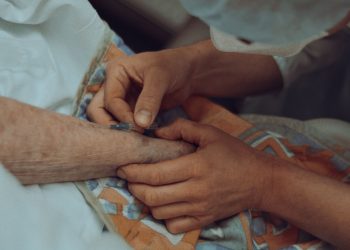 A healthcare professional administers an injection to an elderly patient in a hospital setting.