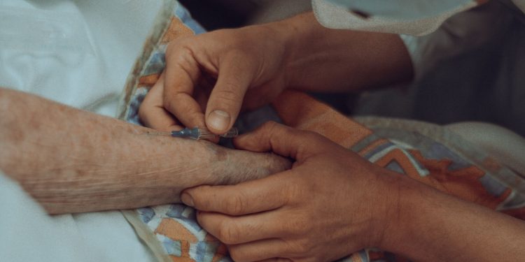 A healthcare professional administers an injection to an elderly patient in a hospital setting.