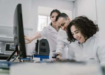 Group of diverse scientists working together on a computer in a bright, modern laboratory.
