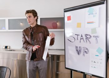 A young entrepreneur gives a presentation on startup strategies indoors with a flip chart.