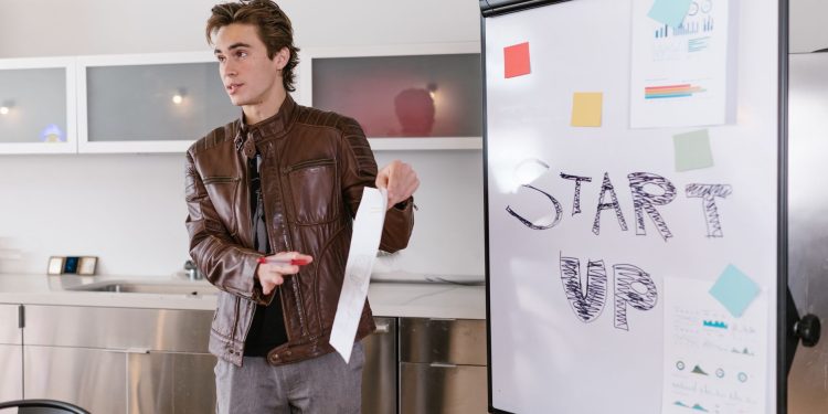 A young entrepreneur gives a presentation on startup strategies indoors with a flip chart.