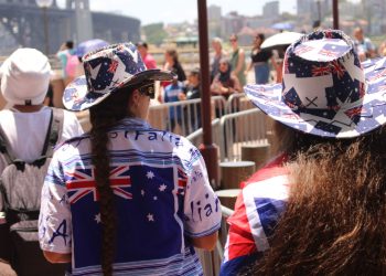 People in Australian attire celebrating at Sydney Harbour under bright sunlight.