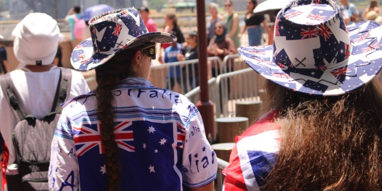 People in Australian attire celebrating at Sydney Harbour under bright sunlight.